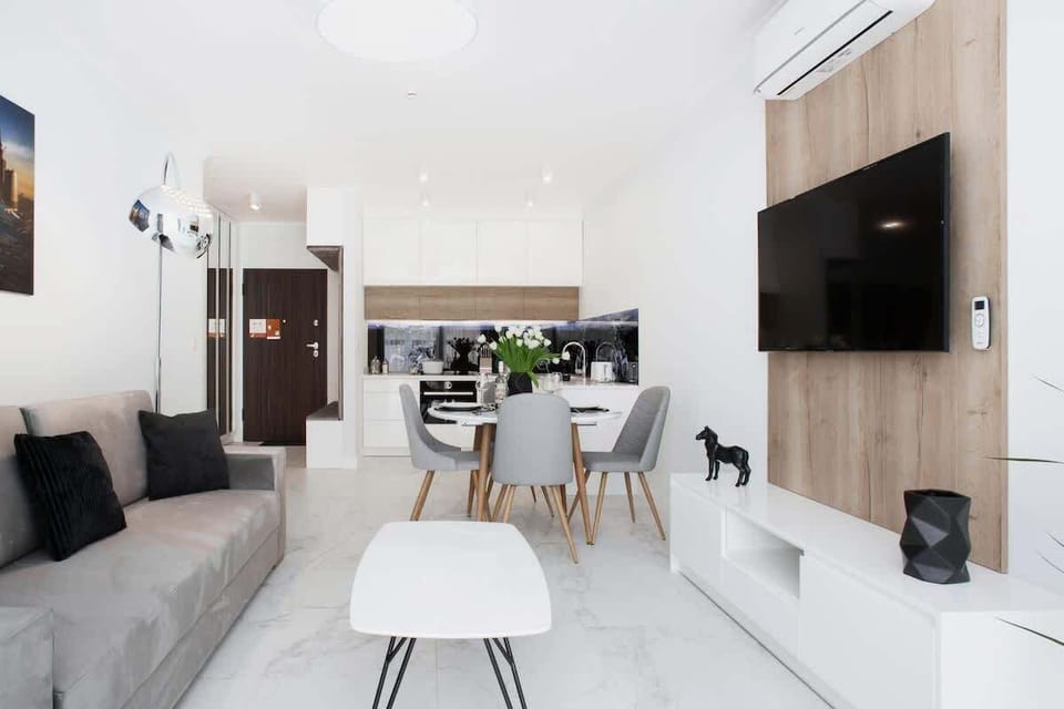 A spacious living room with a TV mounted on the wall, modern decor, and white furniture for a clean look.