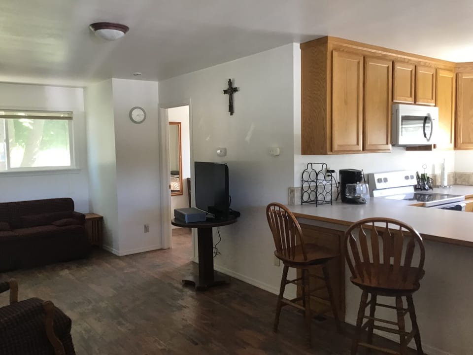 Living area with kitchen and bedroom entrance in background 