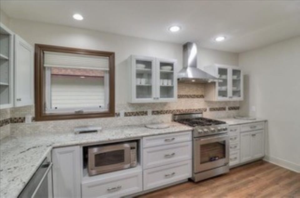 Kitchen with built in microwave, Refrigerator, gas range and vent hood .