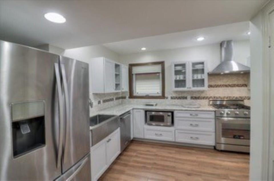 Kitchen with built in microwave, Refrigerator, gas range and vent hood.