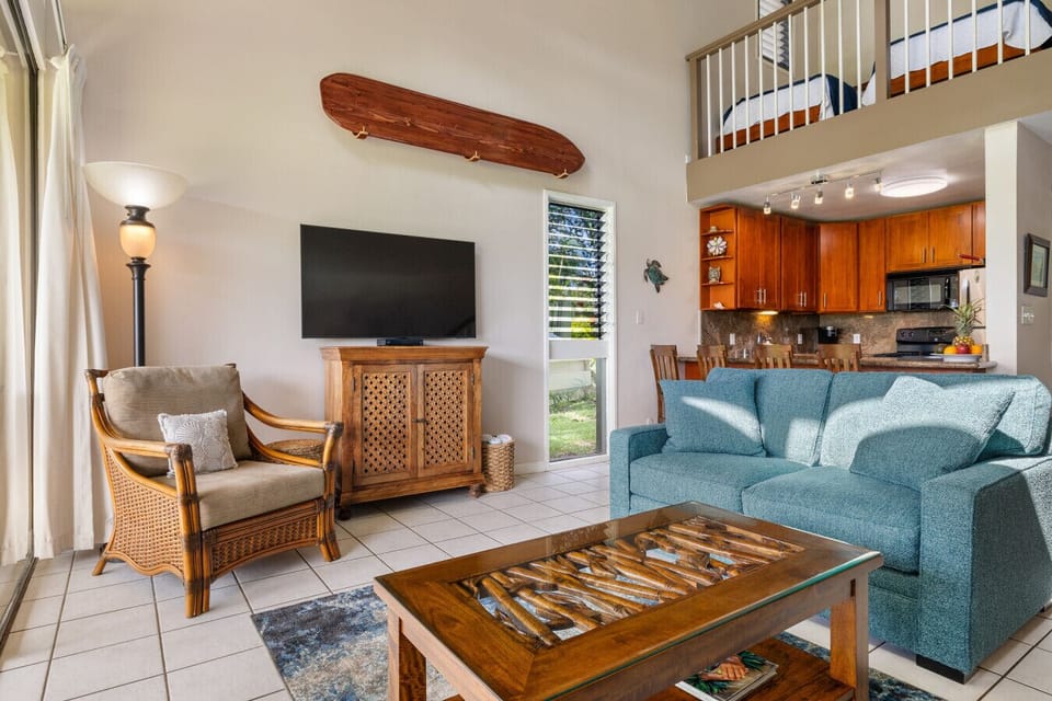 Cozy living area w/ soft seating & sunshine pouring through sliding doors.