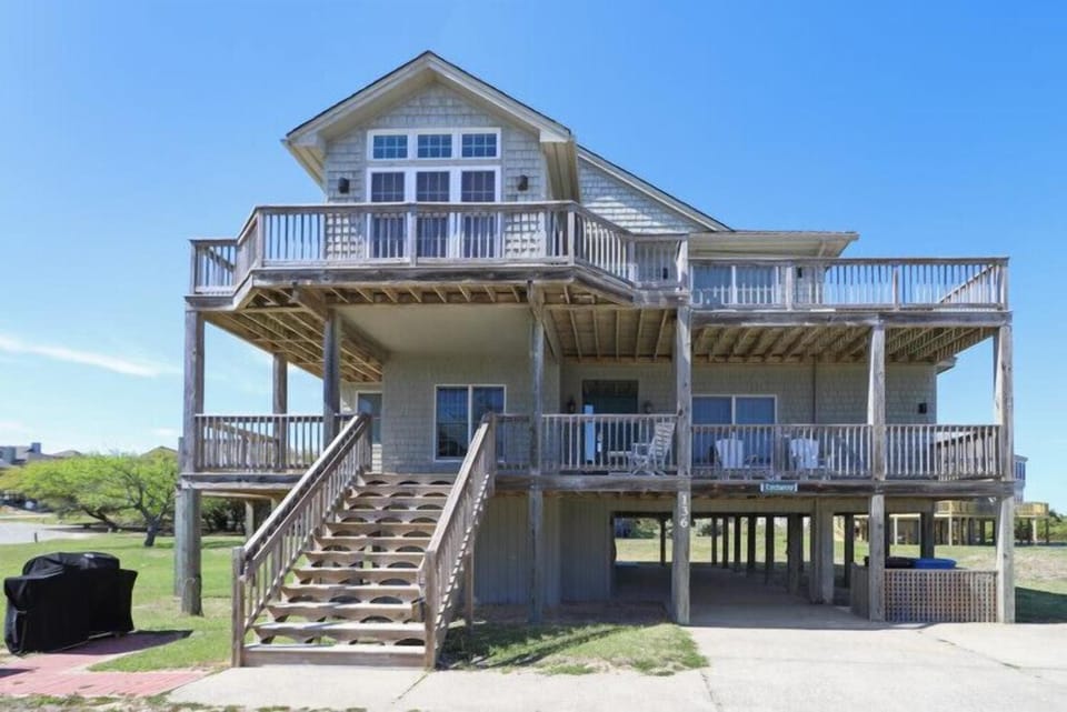 A coastal vacation home elevated on sturdy pilings, featuring multiple wraparound decks and balconies that maximize your views and outdoor enjoyment.