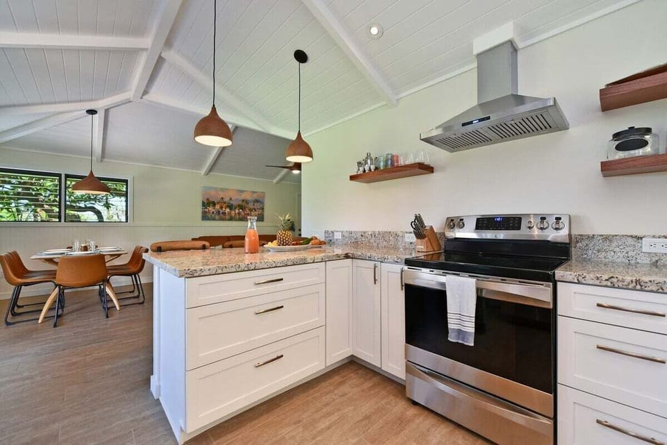 Modern kitchen with stainless steel appliances, white cabinetry, and open shelving.