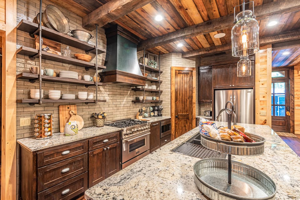 The kitchen houses stainless steel appliances and floating shelves. 