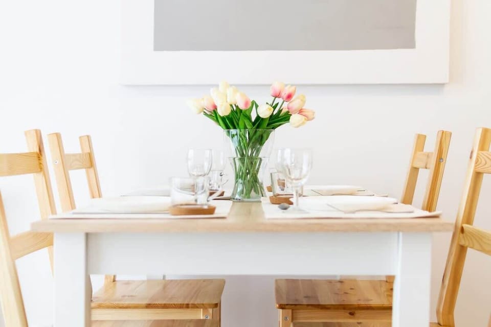 A beautifully set dining table with a flower vase as a centerpiece, creating a welcoming and elegant dining space.