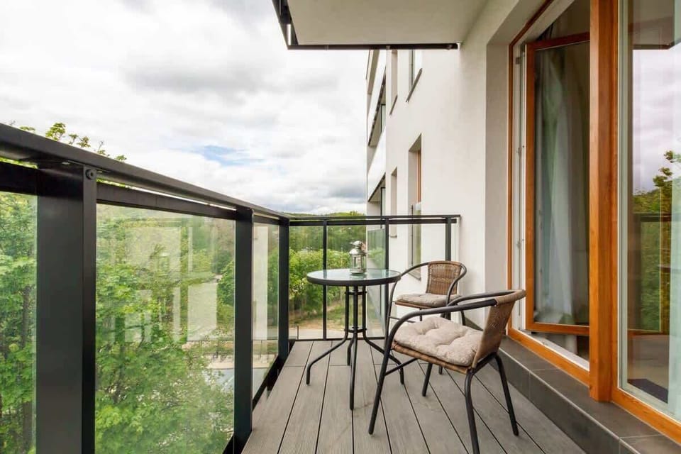 A private balcony with outdoor seating, overlooking greenery and nearby buildings, creating a perfect spot to relax.