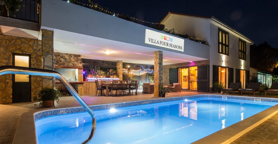Outdoor area with swimming pool, BBQ, covered and open terrace at night.
