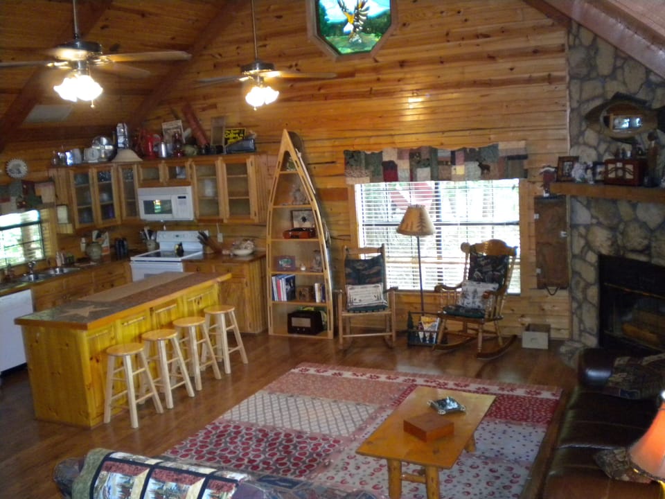 Living room. Cozy cabin feel with fireplace. TV is behind the barstools.
