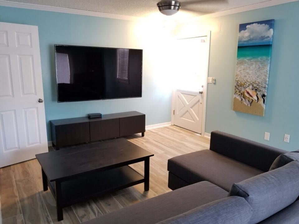 Relaxing living room with large TV and vibrant beach-themed artwork.