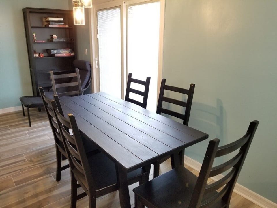 Welcoming dining area with a classic black table and direct access to a sunny balcony.