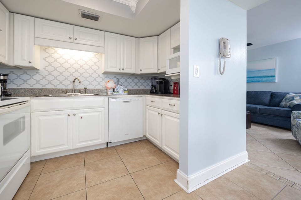 Bright and inviting kitchen featuring white cabinets, granite countertops, a Keurig and a coffee maker for the perfect brew