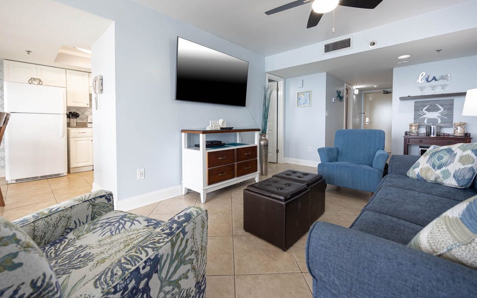 Bright and inviting living area featuring a large TV, cozy seating, additional sleeping, and a charming coastal decor