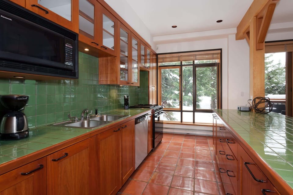 - Fully equipped kitchen with vibrant green tiles and wood cabinetry  
- Modern appliances and ample space for cooking mountain meals  
- Natural light and forest views create a bright alpine kitchen vibe  