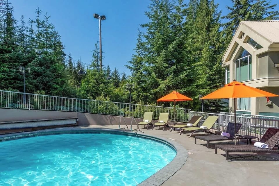 - Outdoor pool surrounded by forest views and sunny lounge seating  
- Relax under bright orange umbrellas and enjoy Whistler’s peaceful nature  
- Perfect for cooling off or soaking up the mountain sunshine in summer  
