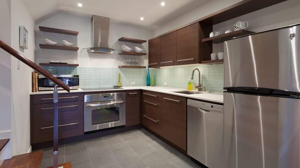 Sleek kitchen w/ stainless appliances, clean lines, and open shelving for effortless home cooking.