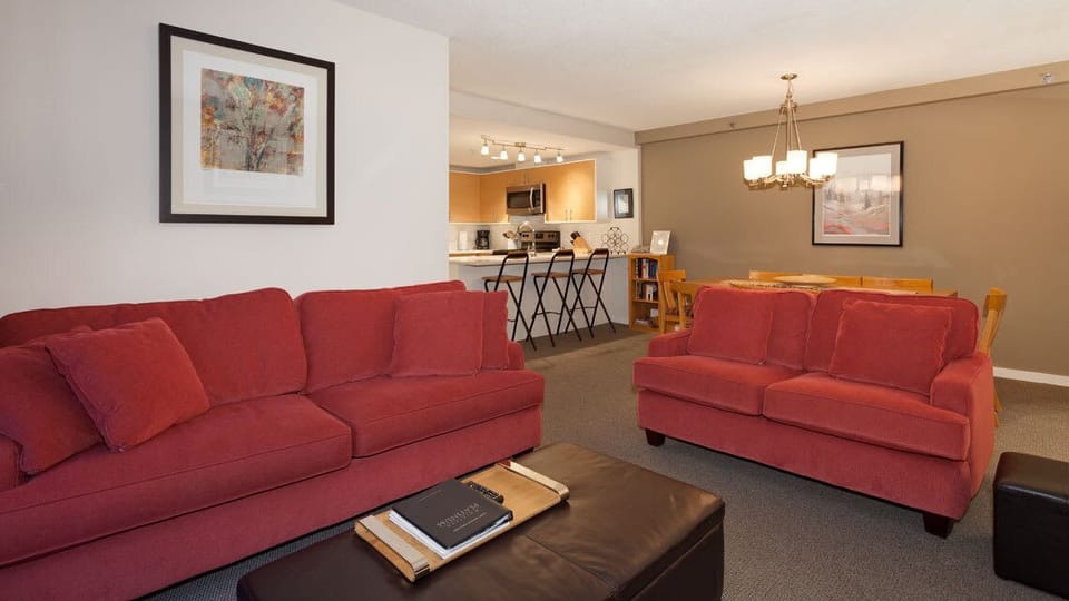 - Cozy living room with vibrant red sofas and warm décor  
- Spacious Whistler condo ideal for family mountain stays  
- Relax and unwind in style after a day on the slopes  
