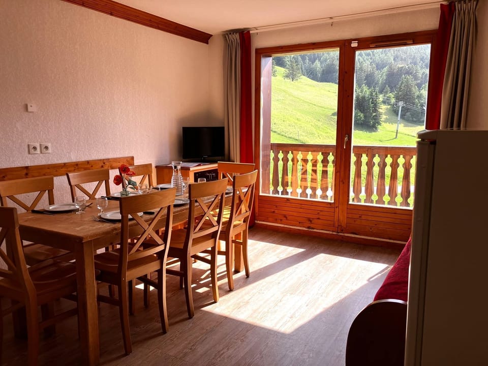 Light spills through the balcony door onto the wooden dining table