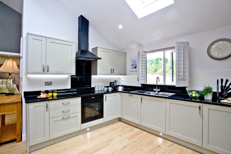Open plan kitchen with grill, induction hob, microwave, large built-in fridge freezer, washer dryer, dishwasher and separate larder units - Oak Lodge