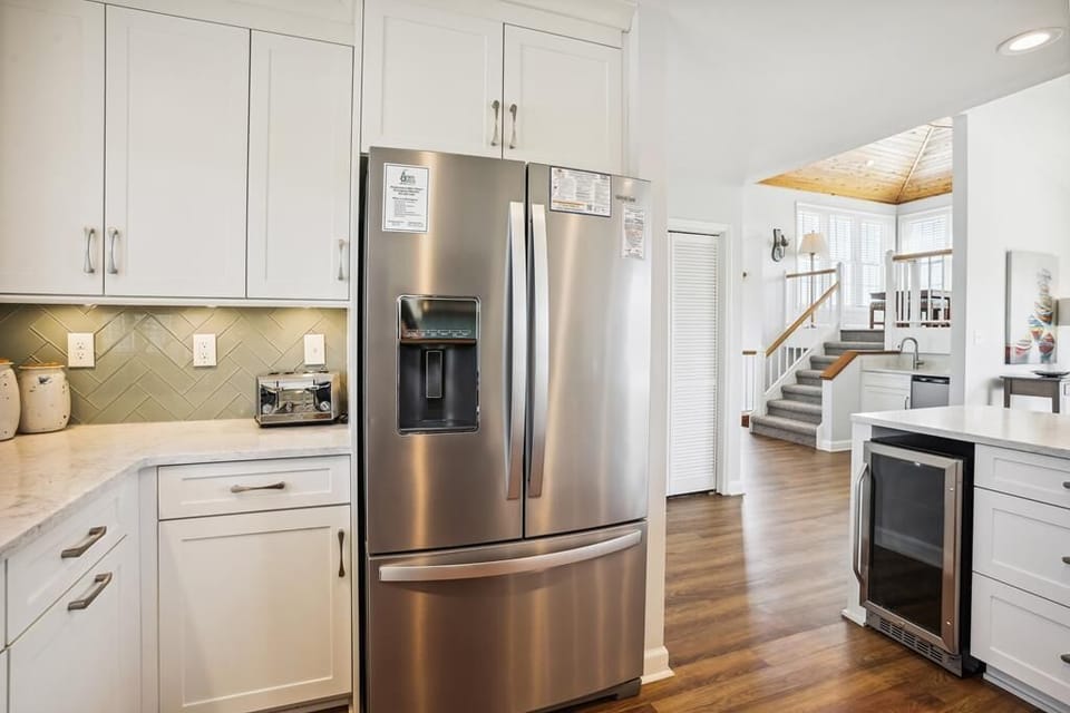 Picture yourself preparing meals in this bright, modern kitchen with gleaming stainless-steel appliances and elegant white cabinetry. The spacious layout flows seamlessly into the living areas, making your vacation cooking a joy.