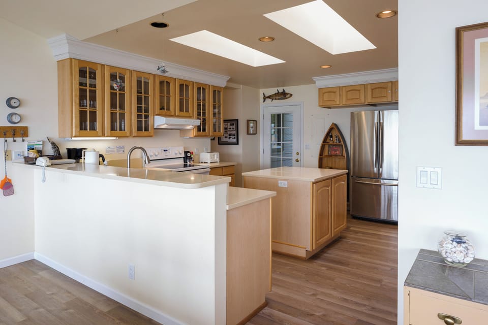 Sun-drenched skylights illuminate your fully equipped kitchen with ample counter space, natural wood cabinetry, and stainless steel appliances—perfect for creating memorable vacation meals together.