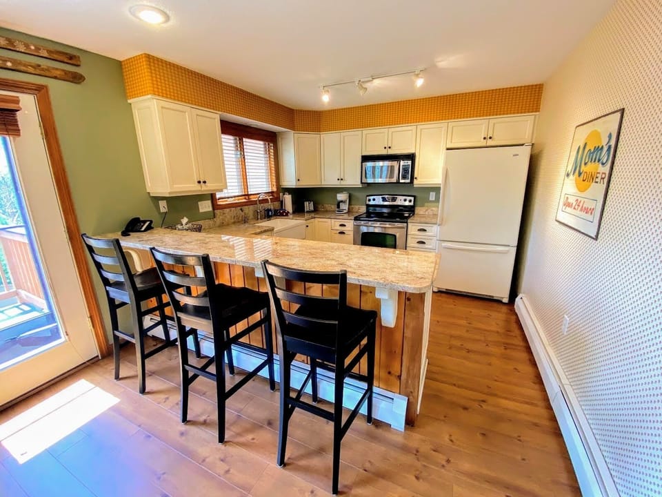 The well equipped kitchen has granite countertops, a drip coffee maker, and breakfast bar seating for four.