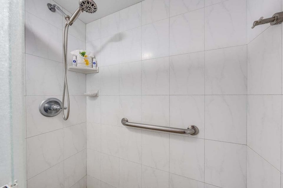 Enjoy a spacious walk‑in shower with clean tile finishes, an easy‑to‑use shower head, and convenient storage shelf