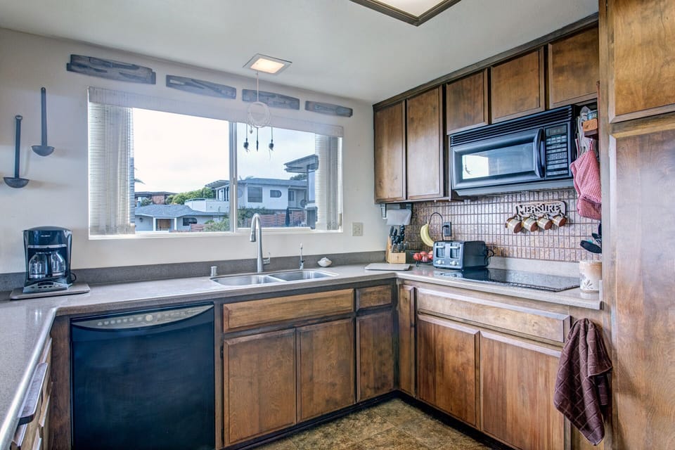 Kitchen with dishwasher, microwave and flattop stove.