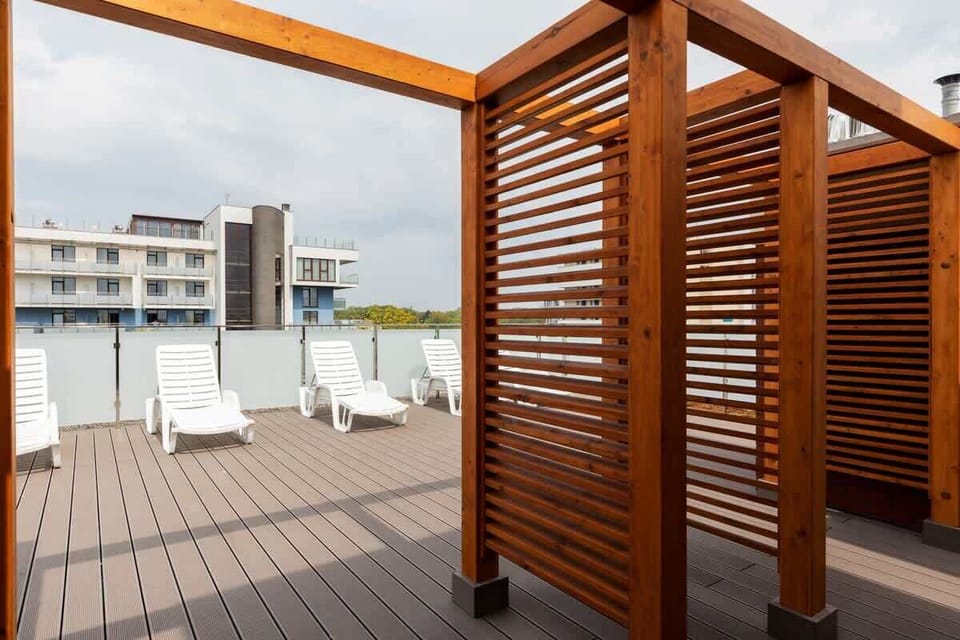 Another part of the rooftop terrace with wooden privacy screens and open seating areas, creating a relaxing outdoor environment for residents.