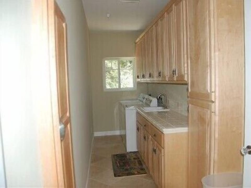Laundry Room has Washer, Dryer, Sink &amp; Built-in Ironing Board. Limestone Floor.