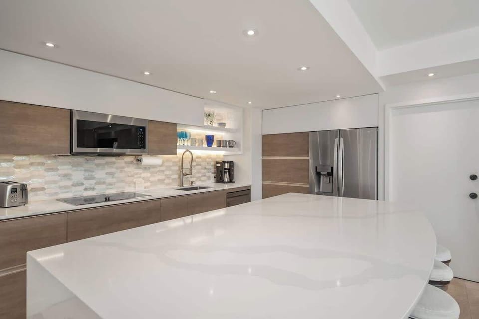 High-end appliance kitchen with fully stocked cutlery and flatware,  induction technology stovetop and Samsung microwave convection oven. Ninja appliances such as coffe maker, Foodie Smart XL indoor Grill, and blender.  
