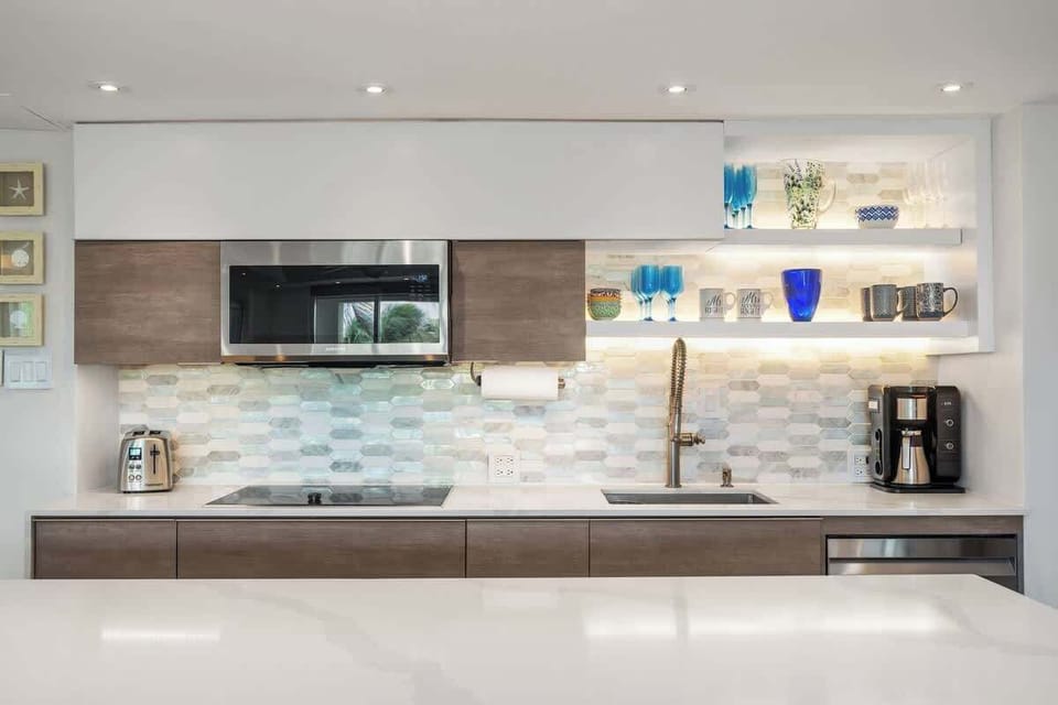 High-end appliance kitchen with fully stocked cutlery and flatware,  induction technology stovetop and Samsung microwave convection oven. Ninja appliances such as coffe maker, Foodie Smart XL indoor Grill, and blender.  