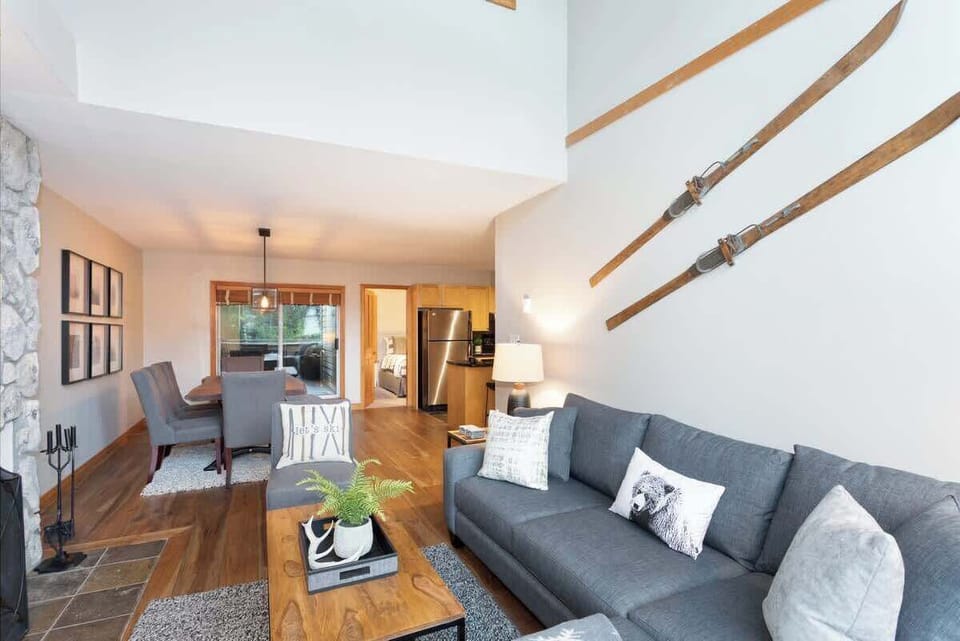 - Stylish living room with cozy gray sofa and vintage ski wall art  
- Stone fireplace creates a warm inviting vibe  
- Perfect for relaxing evenings after outdoor adventures  