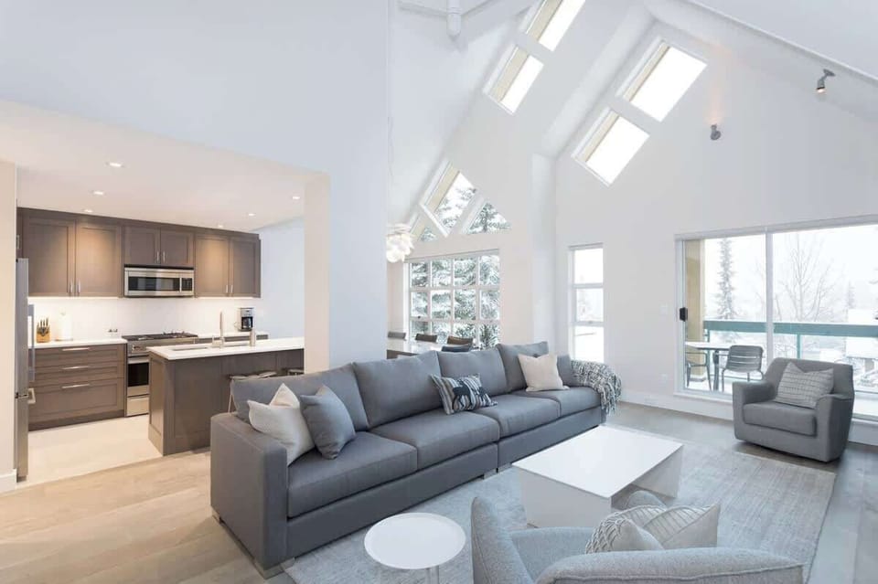 - Spacious living room with high vaulted ceilings  
- Modern open-plan Whistler condo for family stays  
- Bright cozy lounge near slopes and village trails  
