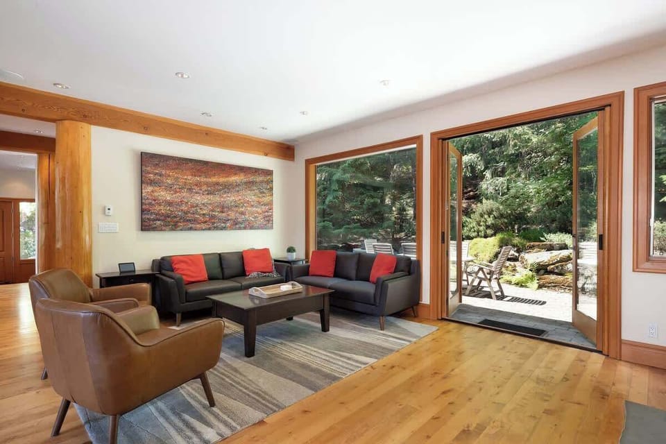 - Bright living area with wood beams and large glass doors opening to nature  
- Comfortable seating and earthy tones create a warm mountain lodge ambiance  
- Step outside to fresh forest air and enjoy seamless indoor-outdoor living