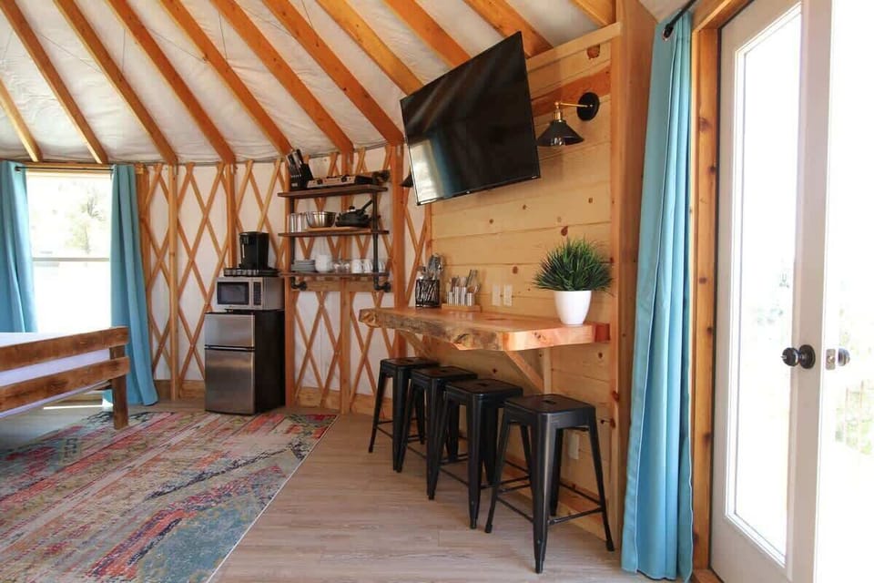Flat-screen TV and bar-style eating area inside your yurt, offering a cozy space to relax, snack, or enjoy a simple meal during your stay.