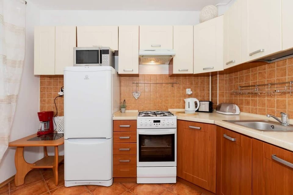 A cozy kitchen with wooden cabinetry, a small table, and two chairs. The dining area is compact and has a warm, inviting feel.
