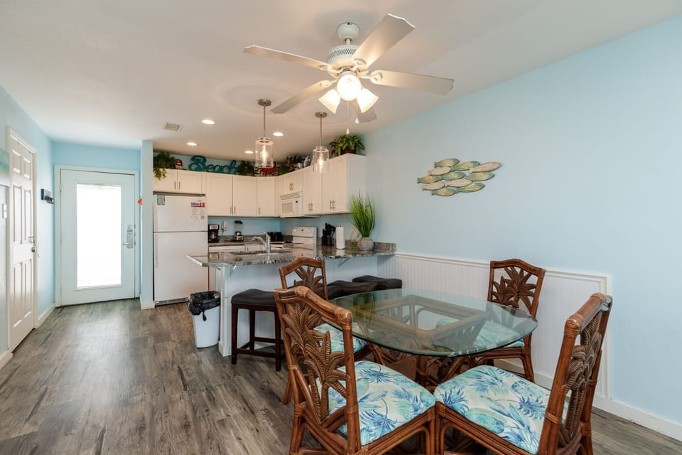 Step into your bright coastal retreat where ocean-themed dining meets fully equipped kitchen convenience, all bathed in soothing sea glass hues.