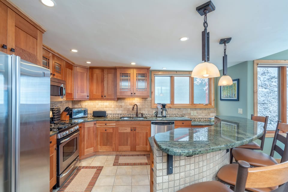 The fully equipped kitchen of this 2 bedroom condo in Telluride, with breakfast bar and stainless steel appliances.