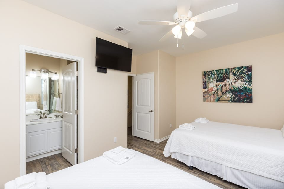 Unwind in your peaceful bedroom with twin beds, ceiling fan, and private bathroom access for ultimate comfort.