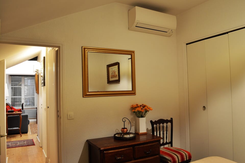 Master bedroom with view towards the living room, with wall mounted AC unit.