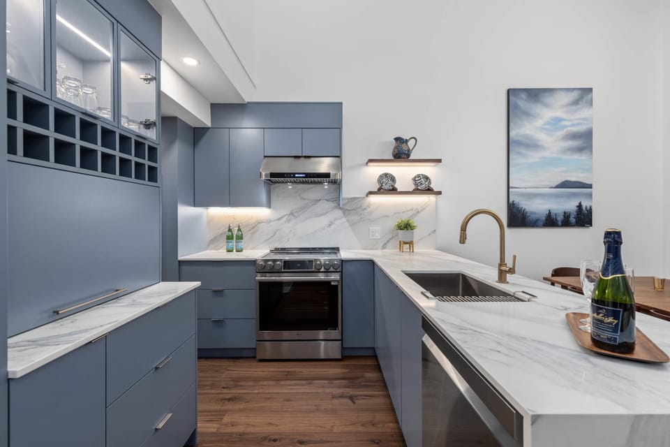 - Sleek kitchen with blue cabinetry and marble countertops  
- Fully equipped with stainless steel appliances and open shelving  
- Ideal for cooking, dining, and entertaining in style  
