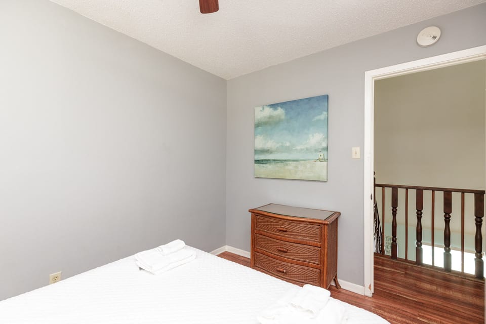 Rest peacefully in your serene bedroom with coastal artwork and warm wood accents creating a tranquil retreat.