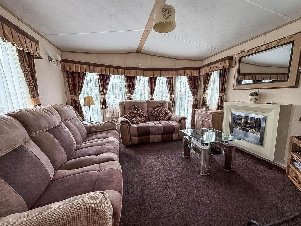 The spacious living room serves as the heart of your accommodation, offering a cosy sanctuary to unwind during your caravan holiday with 2cHolidays.