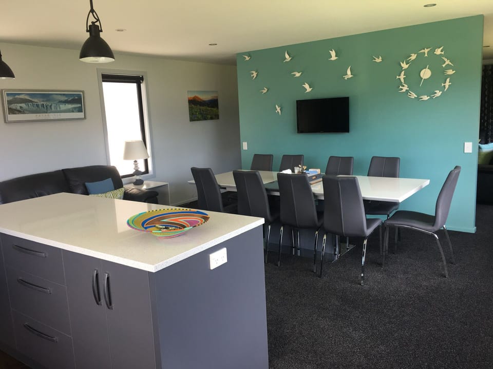 Dining  area also has island bench, couch and TV