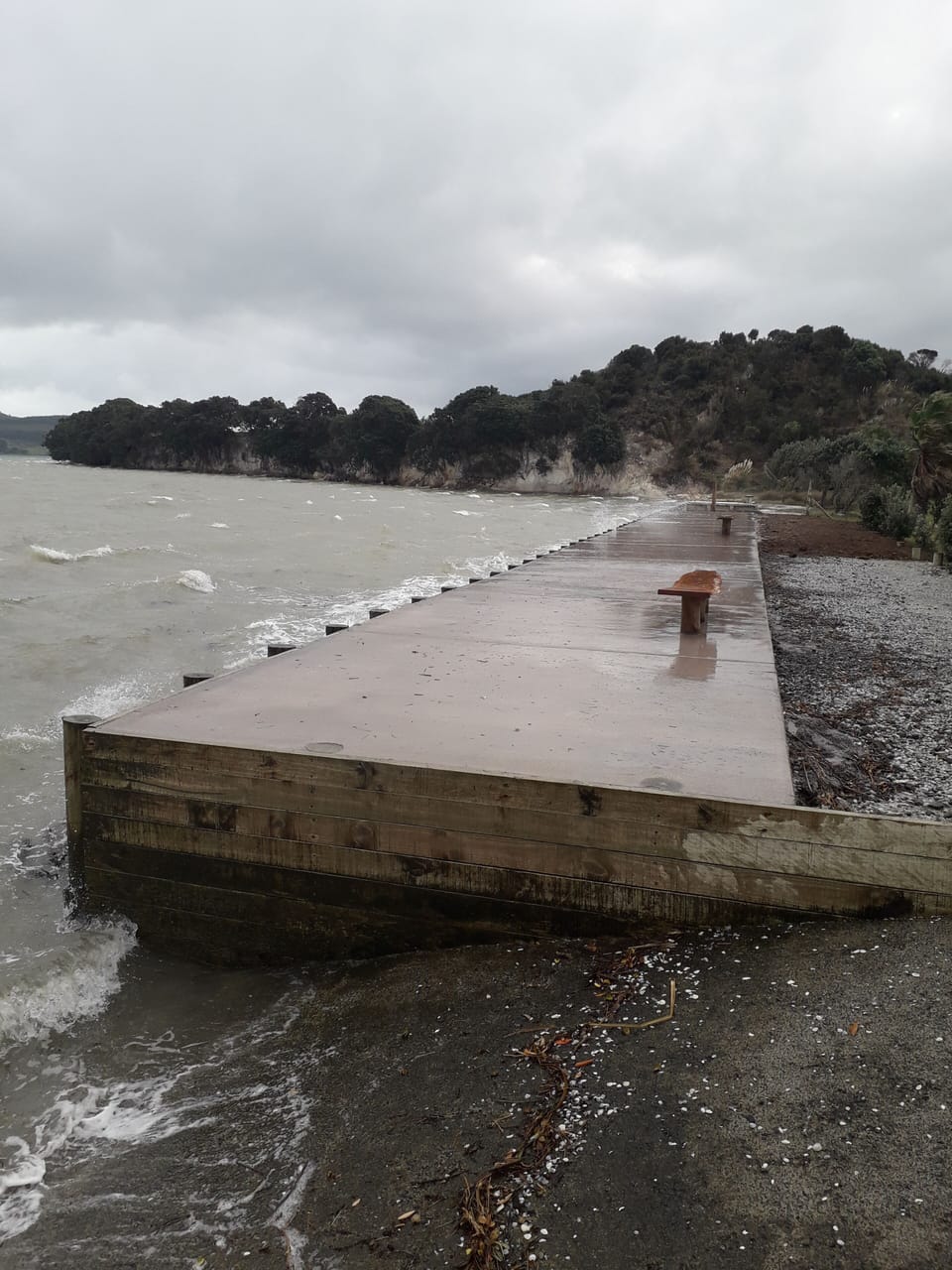 Concrete at beachfront with seating. Wild day at full tide.