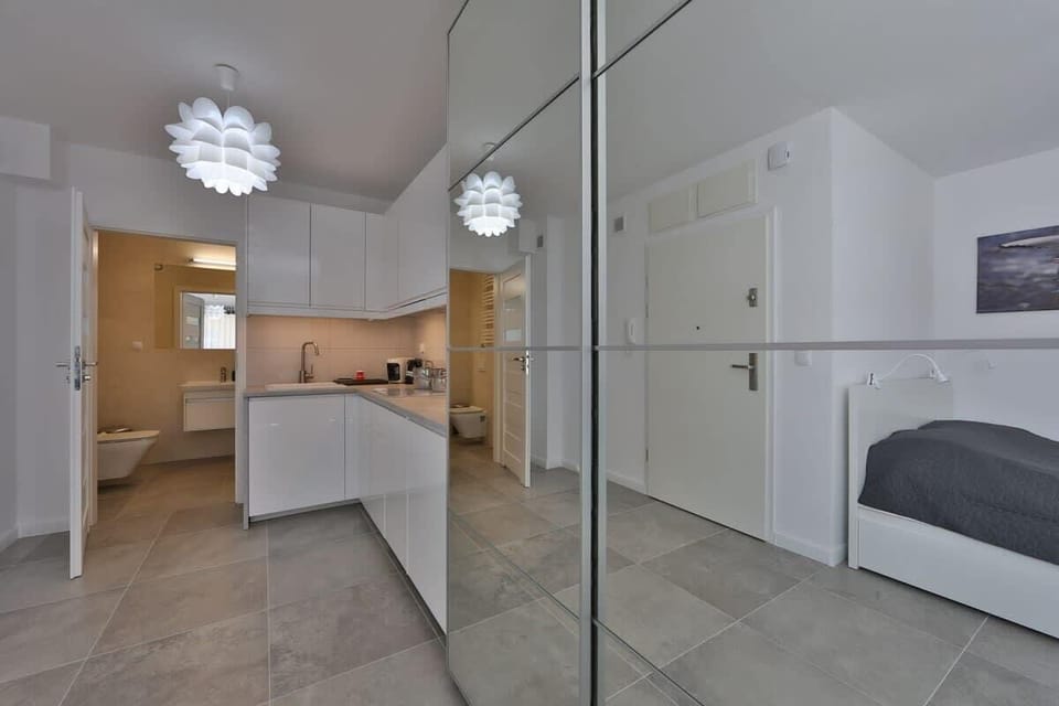 A sleek kitchenette with white cabinetry, integrated appliances, and under-cabinet lighting.