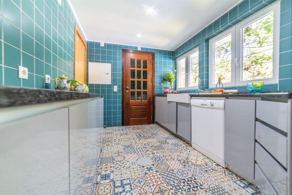 Turquoise tiled kitchen with patterned floor and wooden door — Villa das Begonias, holiday villa in Herdade de Aroeira