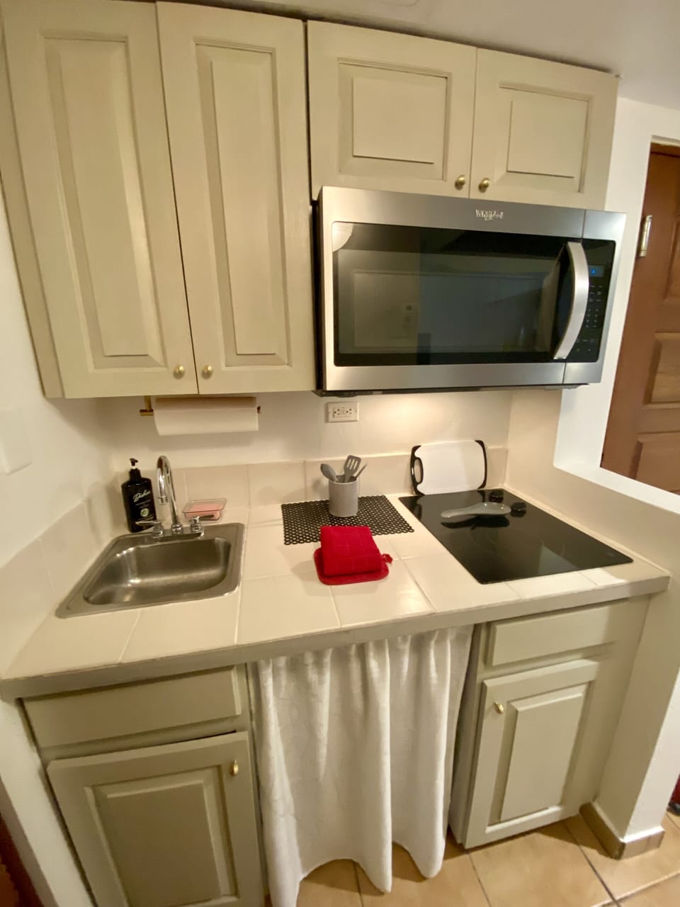 Kitchenette with plates, utensils, coffee maker, pots, and pans.