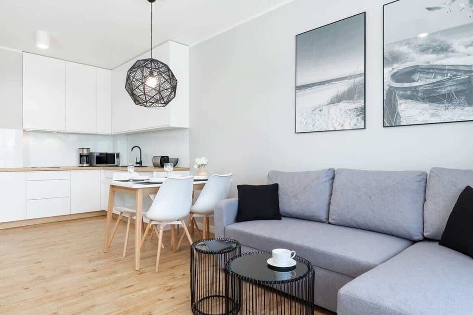 Another angle of the living room, showcasing a grey L-shaped sofa and a modern coffee table against a light-filled backdrop.