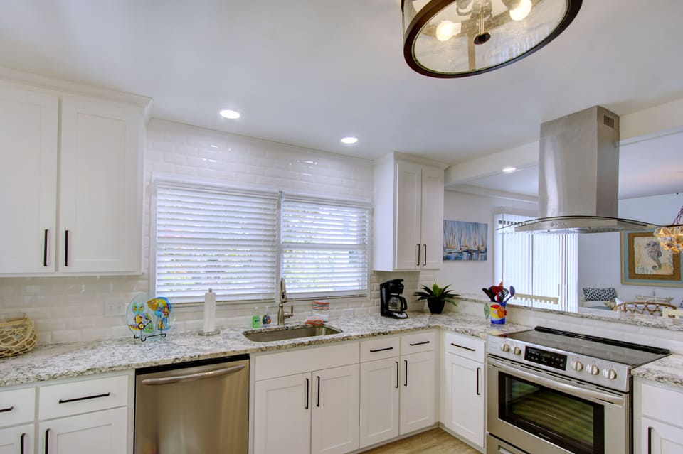 White Kitchen With Gas Range - The renovated kitchen has granite counters, stainless appliances, a gas range, and a full fridge for real cooking during a St. Simons stay.